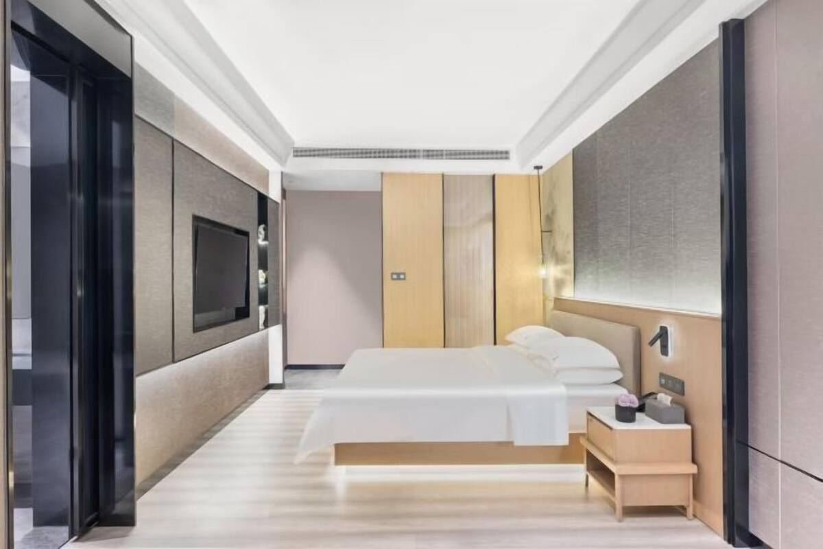 A modern hotel room with a bed, bedside table, and a TV.