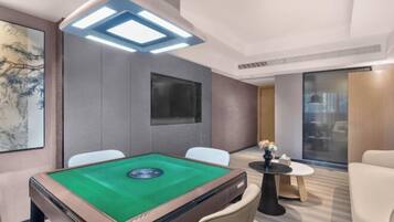 A modern room with a pool table, comfortable seating, a large artwork, and a view through a glass door.
