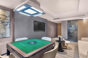 A modern room with a pool table, comfortable seating, a large artwork, and a view through a glass door.