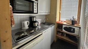A compact kitchen with a stove, microwave, and sink.