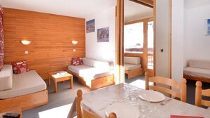 A cozy room with a wooden wall, a sofa, a small table, and a dining table set for two.