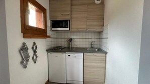 Una cocina compacta con armarios de madera, un microondas, un lavavajillas y una ventana sobre el fregadero.