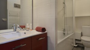 Un baño moderno con un lavabo blanco, una cabina de ducha de vidrio y un inodoro.