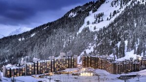 Ein schneebedecktes Bergresort mit mehreren Hochhäusern, Skiliften und einer Skipiste.