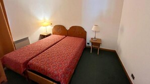 Ein Hotelzimmer mit einem Doppelbett, zwei Nachttischen und einem Beistelltisch mit Lampen.