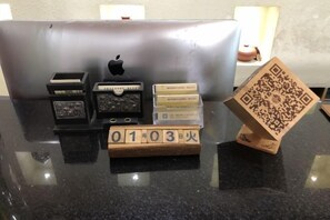 A desk with a laptop, a wooden block with a QR code, and several small containers.