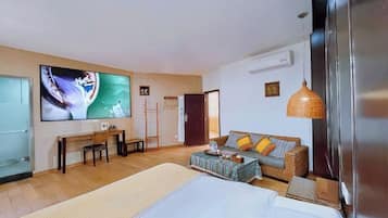 Una habitación de hotel con una cama, un sofá, un escritorio, un televisor y un ventanal grande.