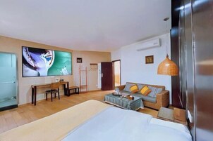 Una habitación de hotel con una cama, un sofá, un escritorio, un televisor y un ventanal grande.