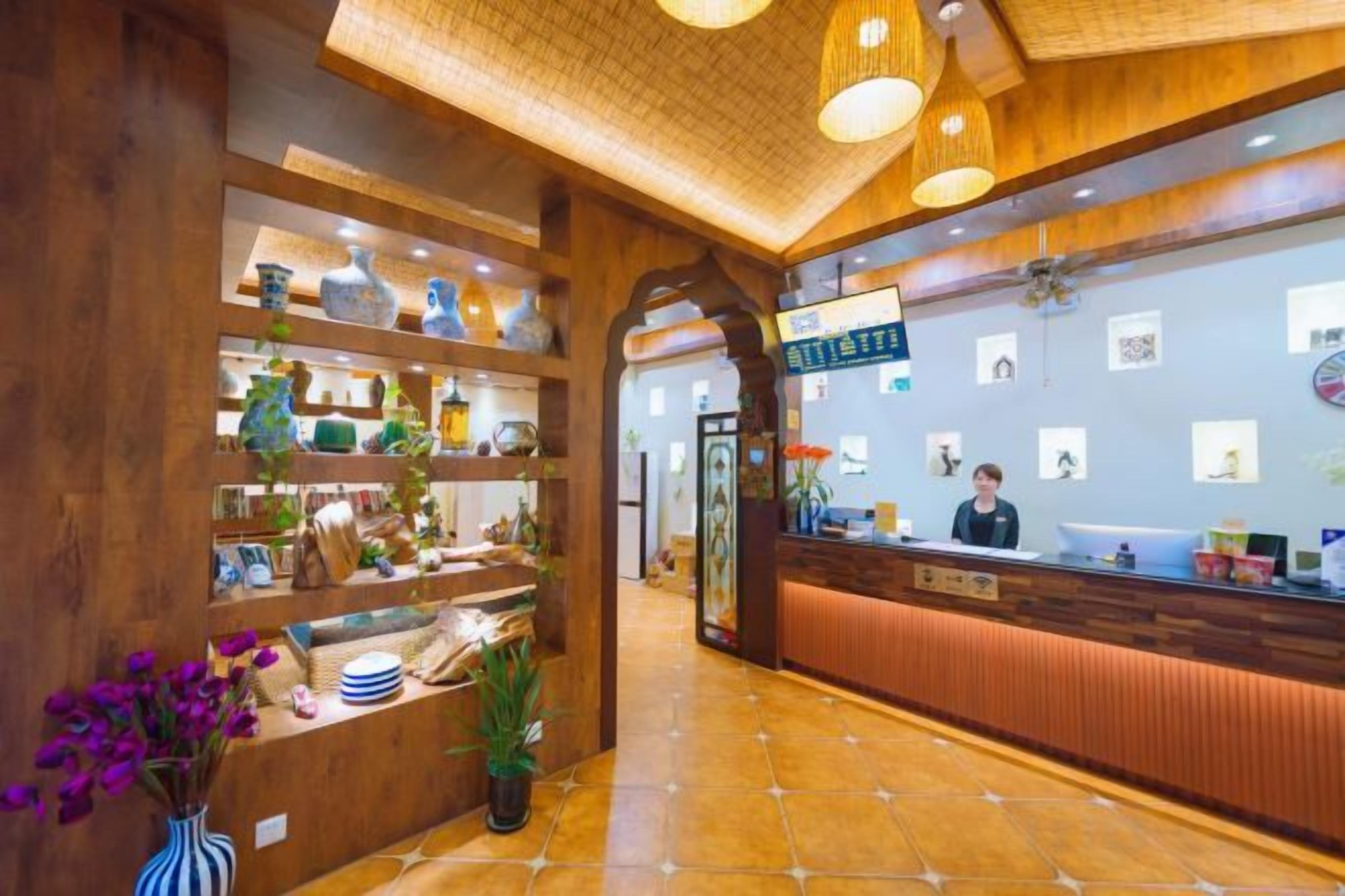 A reception area with a wooden reception desk, shelves with decorative items, and a tiled floor.