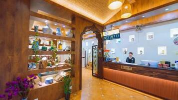 A reception area with a wooden reception desk, shelves with decorative items, and a tiled floor.