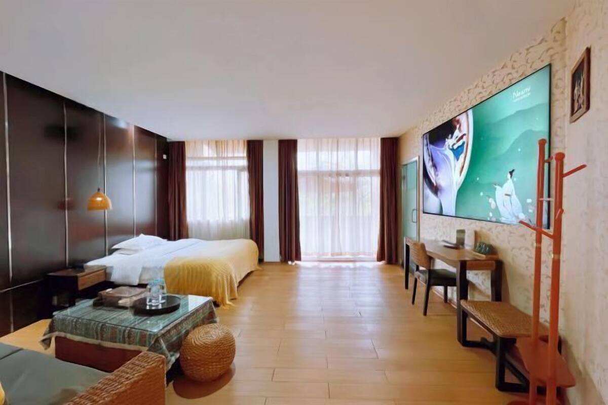 A hotel room with a bed, a desk, a TV, and a view of the outdoors.