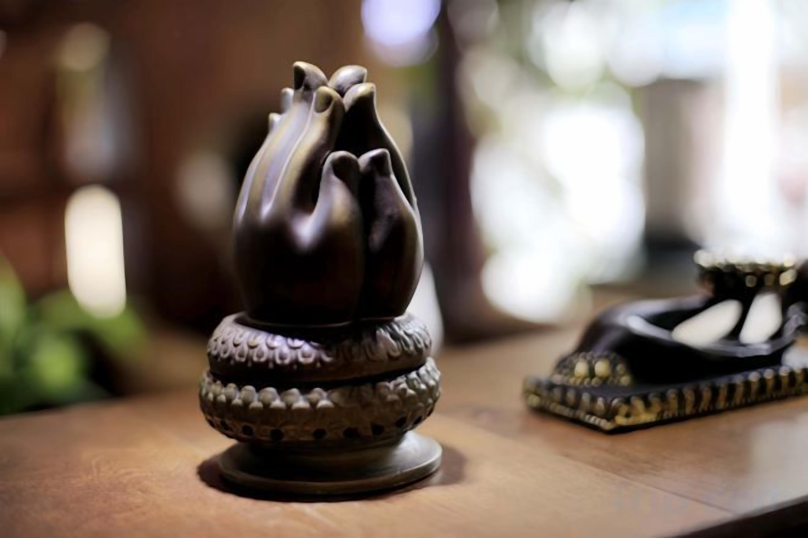 A dark-colored, ornate object with a floral design on a wooden surface.