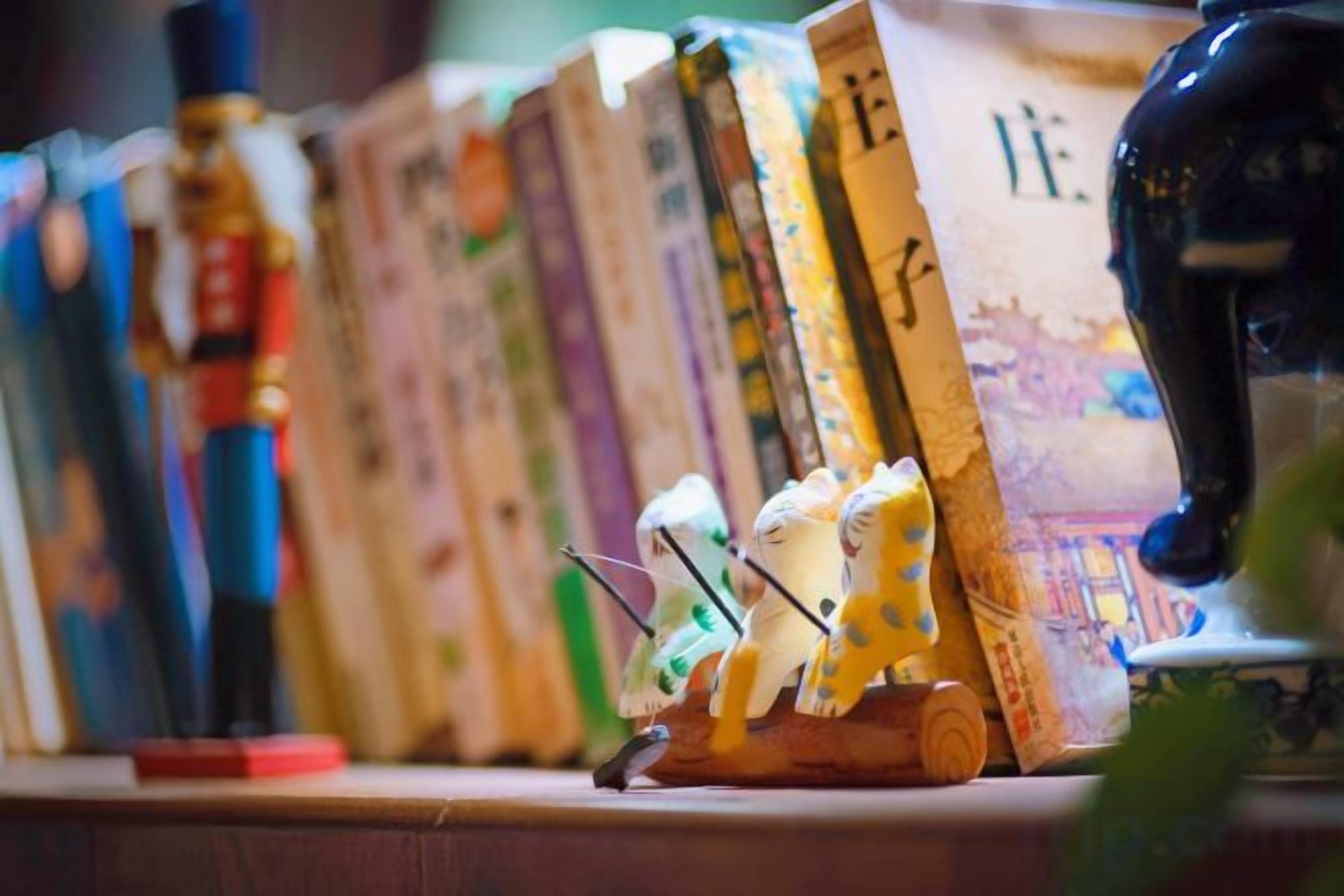 Una fila de libros en un estante con una figura cerámica decorativa a la derecha.