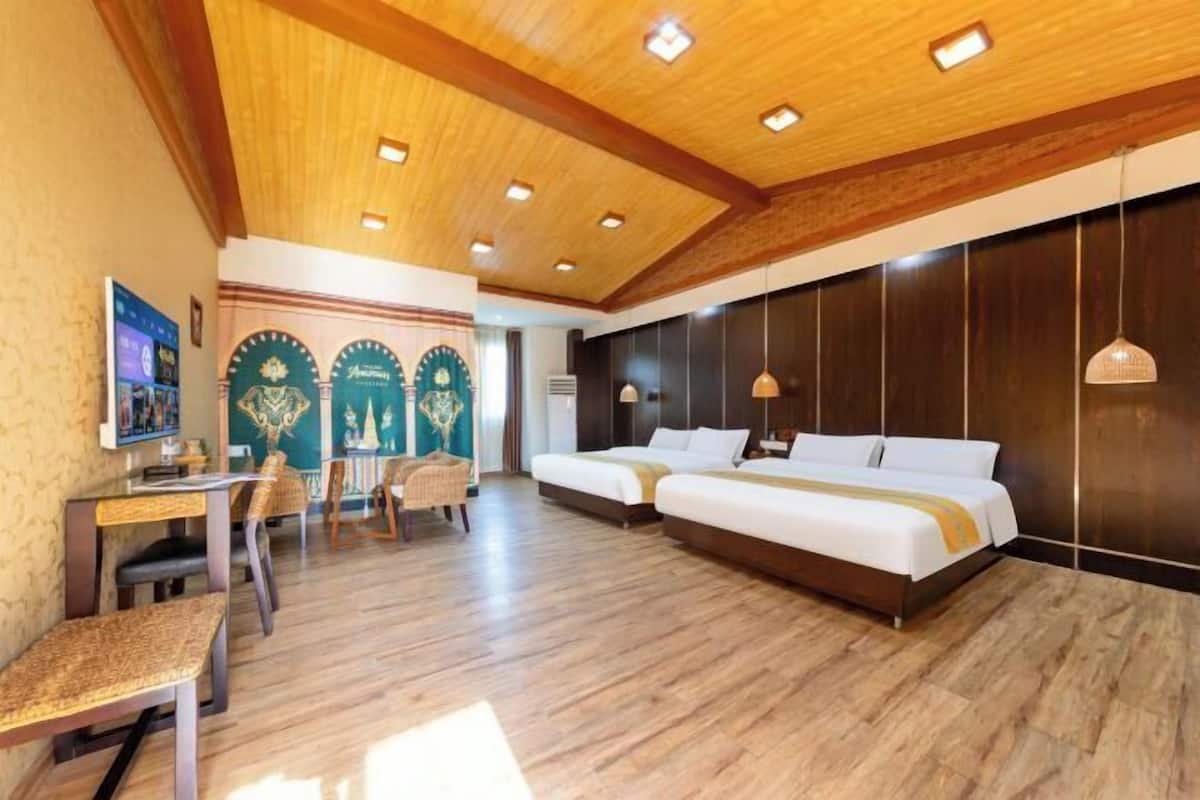 A hotel room with a wooden ceiling, two beds, a desk, and a chair.