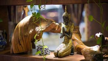 Una repisa de madera con una estatua, un tronco de madera tallado y un pequeño objeto decorativo.