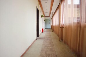 A corridor with a carpeted floor, wooden paneling on the walls, and a door on the left. - Bati Yangguang Chain Hotel Meizhou Meilong (Meizhou)