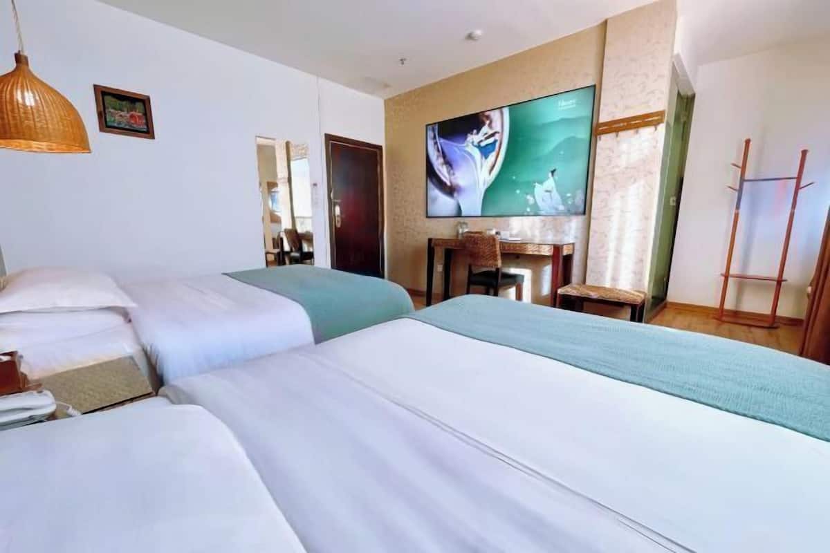 A hotel room with two beds, a TV, a dining table, and a chair.