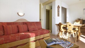 A living room with a red sofa, wooden dining table, and chairs.