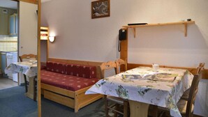 A cozy room with a wooden bench, a table with a floral tablecloth, and a wall-mounted phone.