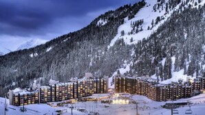 A snow-covered mountain resort with multiple hotel buildings, ski lifts, and a ski slope.