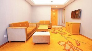 A living room with a sofa, ottoman, and a TV mounted on the wall. - Vienna Hotel (Nanning People's Park Minzhu Rd) (Nanning)