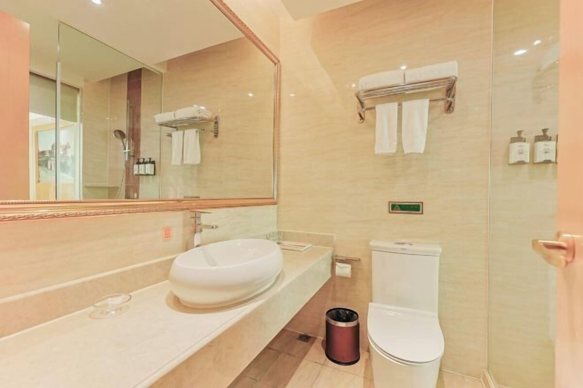 A modern bathroom with a large mirror, a sink, a toilet, and a glass shower enclosure.