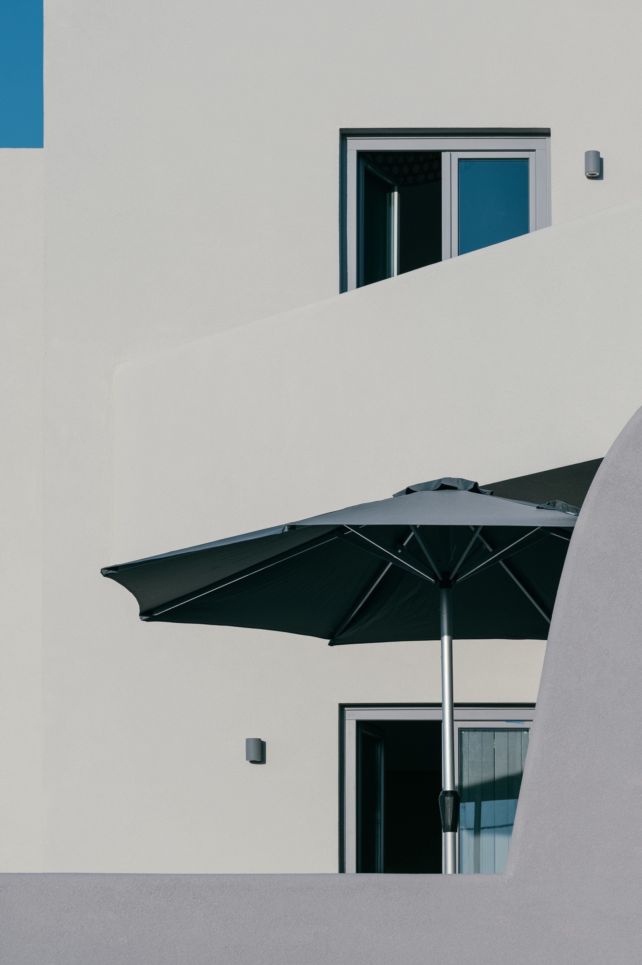 A building with a large window and a door, and a black umbrella in front.