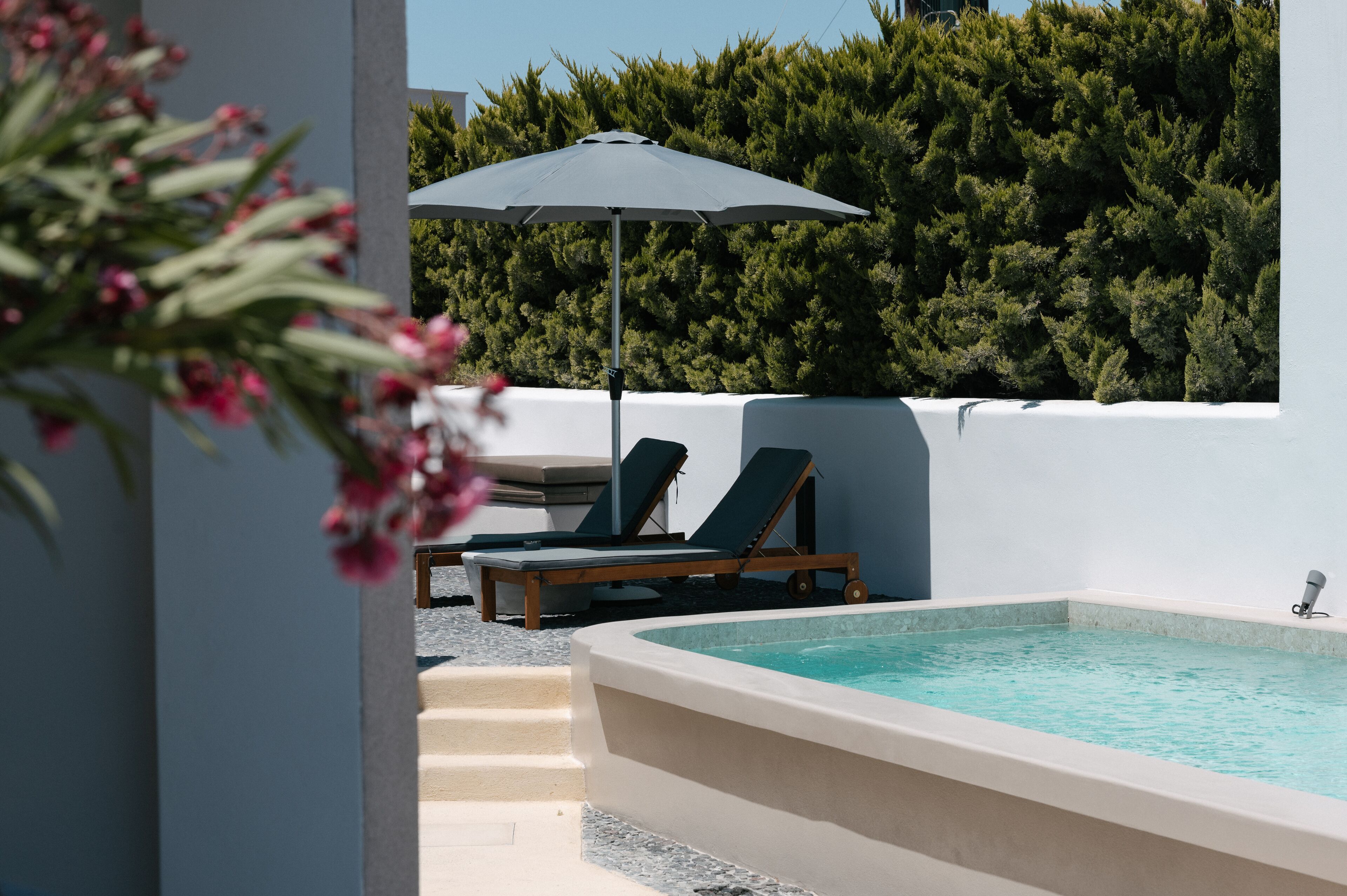 Un área de piscina con jacuzzi, sillas de descanso y una sombrilla.