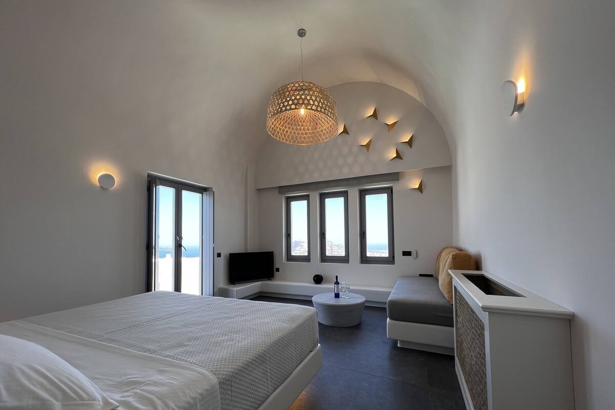 A modern bedroom with a large bed, a seating area, and a TV.