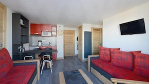 A compact living space with a kitchenette, a dining area, and a seating area with red sofas. - 100m from ski slopes, 2nd floor, view mountain, balcony, tv, ski locker, 32m², Montchavin La Plagne (Bellentre)