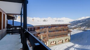 A snow-covered mountain landscape with a building featuring multiple balconies and a wooden facade.