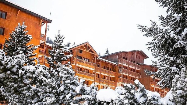 A multi-story wooden building with balconies, surrounded by snow-covered trees. - 70m from ski slopes, 4th floor, view mountain, balcony, parking, tv, ski locker, 20m², Valfréjus (Valfréjus)