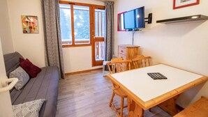 A cozy room with a sofa, a dining table, and a TV. - 70m from ski slopes, 4th floor, view mountain, balcony, parking, tv, ski locker, 20m², Valfréjus (Valfréjus)