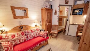 Ein gemütliches Zimmer mit einem hölzernen Bett, einem Holzschrank, einem kleinen Tisch und einer Küchenzeile.