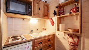 Eine kleine Küche mit Mikrowelle, Herd, Spüle und Holzschränken.