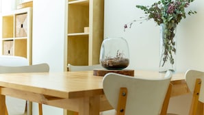 A wooden dining table with chairs, a glass terrarium, and a vase with flowers. - V010 - Milenium, Apartamento con piscina comunitaria y acceso a la playa. (Roses)