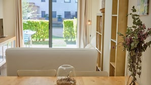 A dining table with a clear glass bowl containing a nest, a vase with dried flowers, and a view of a garden through a window. - V010 - Milenium, Apartamento con piscina comunitaria y acceso a la playa. (Roses)