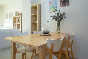 A dining area with a wooden table, white chairs, a glass dome centerpiece, and a vase with flowers.