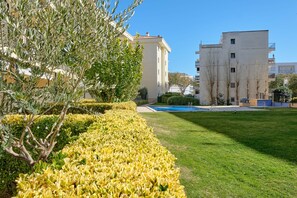 A well-maintained garden with a swimming pool, surrounded by buildings.