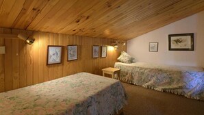Una stanza con pannelli in legno, due letti, un tavolino e quadri appesi alle pareti.