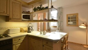 Una cucina con mobili in legno, un forno a microonde, un bollitore e un'area pranzo con tavolo e sedie.
