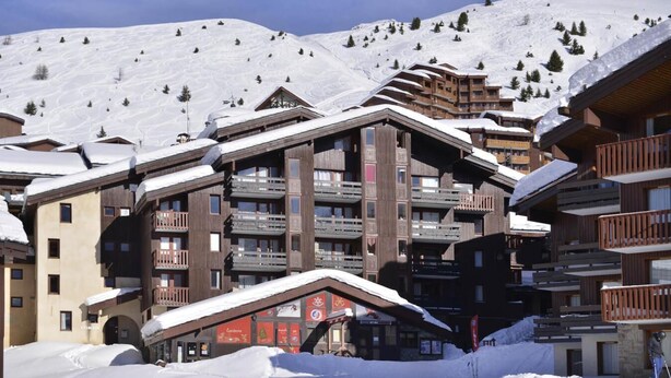 Una stazione sciistica con edifici a più piani, impianti di risalita e pendii innevati.