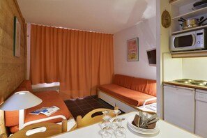 Cozy single-room accommodation with a kitchenette, dining area, and comfortable bed.