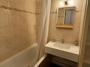 Ein Badezimmer mit Badewanne, Waschbecken, Spiegel und Duschvorhang.