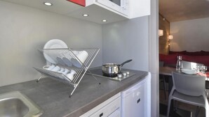 A modern kitchen with a dish rack, a stove, and a microwave. There is a dining area with a table and chairs. - 100m from ski slopes, 8th floor, view ski slopes, balcony, tv, ski locker, 28m², La Plagne (La Plagne)