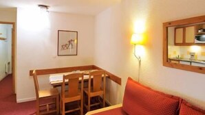 A small room with a wooden desk, two chairs, a red sofa, a wall-mounted lamp, and a framed picture. - 100m from ski slopes, terrace, tv, 23m², Montchavin La Plagne (Bellentre)