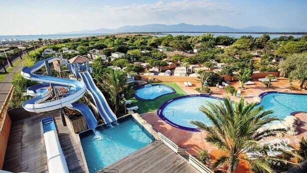Een resort met meerdere zwembaden, een glijbaan en uitzicht op het omliggende landschap.