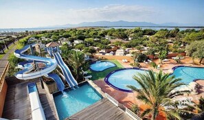 A resort with multiple swimming pools, a water slide, and a view of the surrounding landscape.
