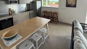 A modern kitchen with wooden beams, a dining area with stools, and a view of the outdoors.