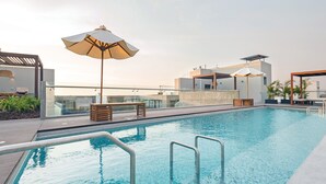 A rooftop pool with clear blue water, surrounded by modern outdoor furniture and umbrellas. - ✶ Maras Residence ✶ LUXURY Rooftop Pool & Grill (Miraflores)